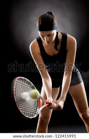 Female tennis player with racket and ball on black background