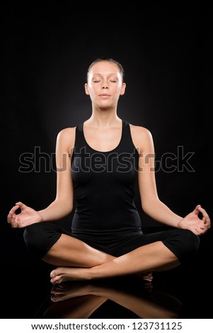 Young woman sitting in lotus position meditating with eyes closed