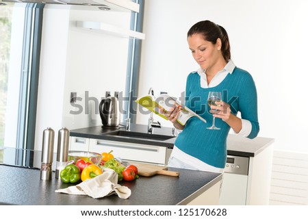 Woman housewife reading cooking book recipe kitchen wine vegetables