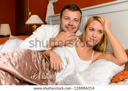 Smiling husband holding wife lying bed daydreaming married couple