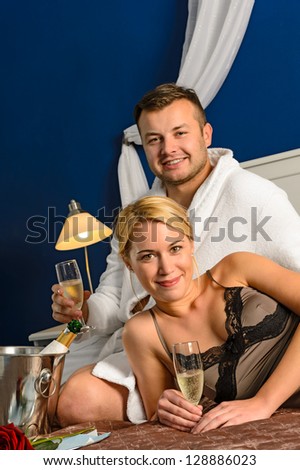 Intimate affair bed young couple drinking champagne woman nightgown