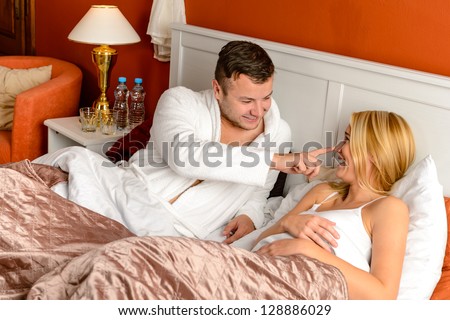 Young man stroking woman lying bed happy couple motel room
