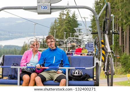Chair lift going through forest while happy couple sitting