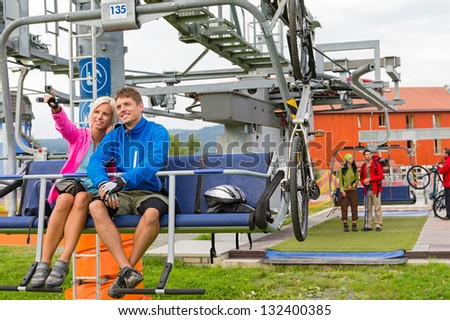 Happy couple traveling by chair lift enjoying landscape