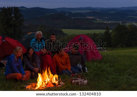 During night camping friends setting fire beside tents