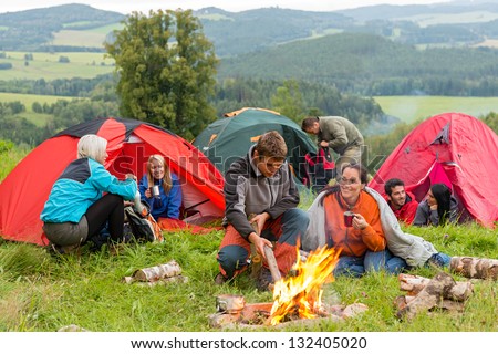 Group of young students spending weekend together in tents campfire