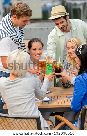 Group of cheerful young people toasting with cocktails outdoor terrace