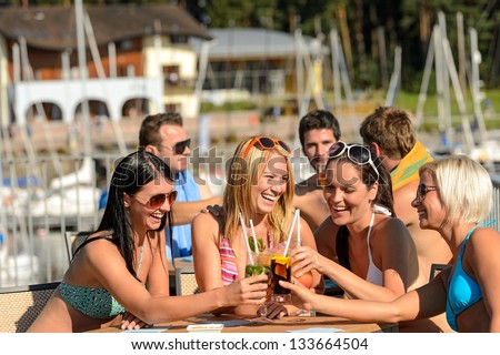 Beautiful women in bikinis toasting with cocktails at beach Beautiful women in bikinis toasting with cocktails at beach