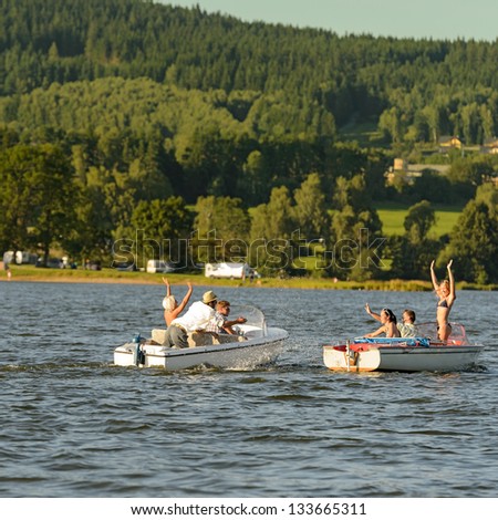 Young people having fun on motorboats on lake summertime