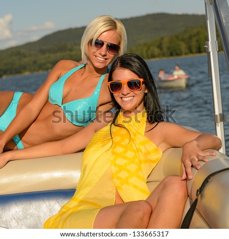 Young happy women sunbathing on boat enjoying summer