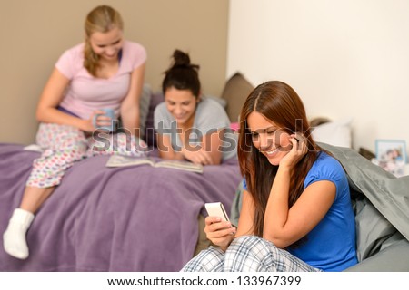 Smiling teenager girl sending text message at pajama party