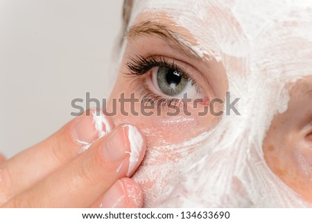 Young girl fingers applying face mask moisturizer cleaning skin
