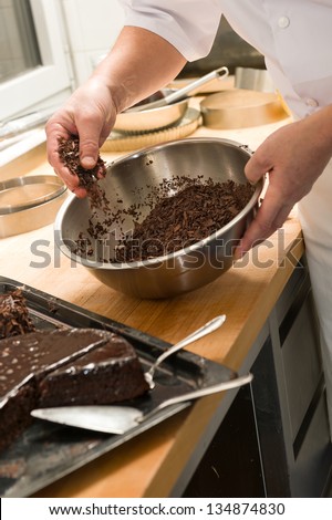 Chef decorating chocolate cake with dark brown icing sugar