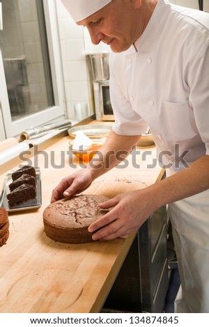 Middle aged cook placing chocolate cake in hotel\'s kitchen