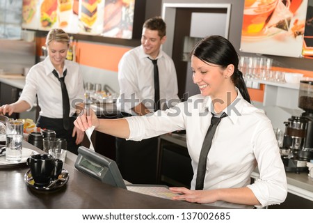 Female Cashier Giving Receipt Colleagues Working In Cafe