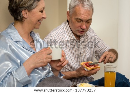 Elderly couple eating romantic breakfast together in bed