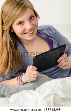 Happy young girl using digital tablet for studying