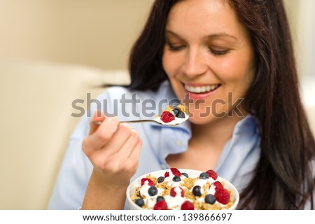 Relaxed woman eating bowl of cereal for breakfast