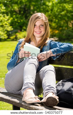 Young female student studying in the park sitting on bench