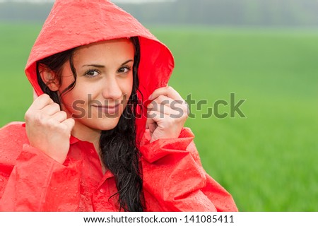 Adolescent girl smiling in the rain in red raincoat