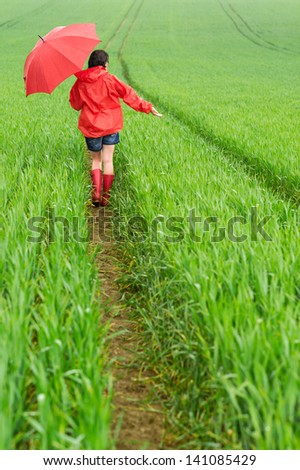 Lonely girl walking in the rain in rubber boots