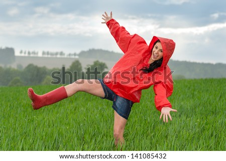 Playful teenage girl dancing in the rain on a field