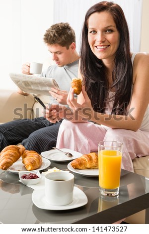 Smiling couple eating romantic breakfast in hotel room