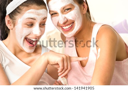 Laughing caucasian girls wearing peeling mask having fun