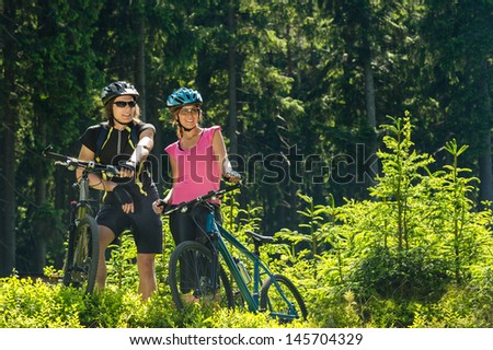 Mountain bikers standing and resting in forest sunny nature