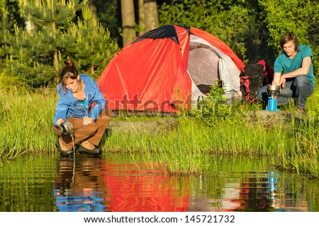 Camping couple heating the supper and washing pot