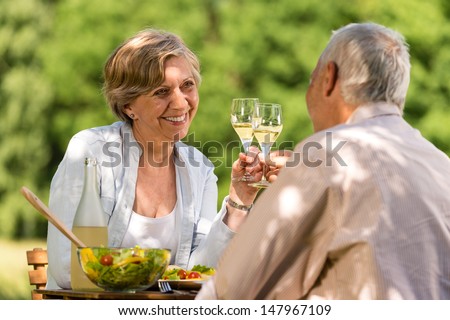 Happy senior citizens clinking glasses in garden