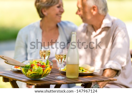 Cheerful senior citizens dating and eating outdoors