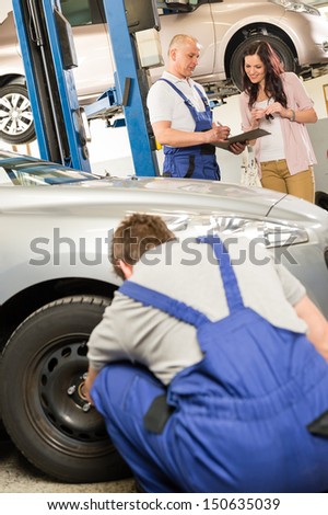 Mechanic showing  paperwork to car owner in garage