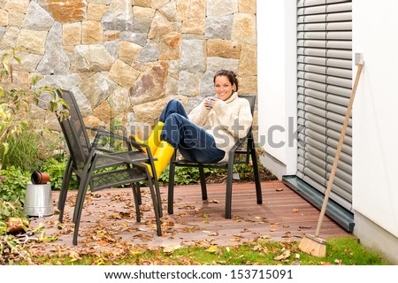 Happy woman relaxing autumn housework drinking coffee fall patio
