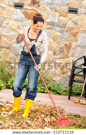 Smiling woman raking leaves autumn fall garden housework