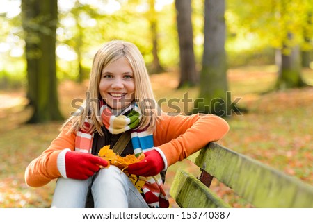 Smiling blonde teenager girl sitting autumn park bench nature forest
