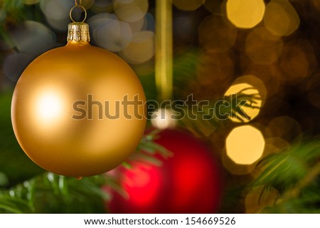 Gold christmas bauble hanging on Xmas tree sparkling lights background