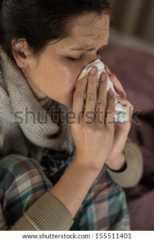 Close up portrait of woman sneezing into tissue