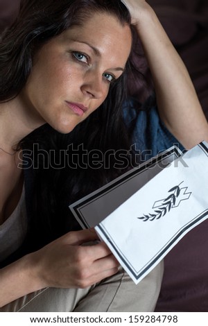 Close up portrait of young widow holding obituary