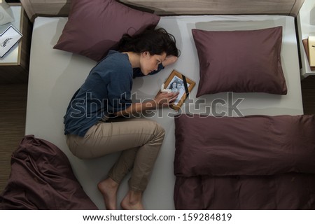 Young mourning woman lying in bed alone