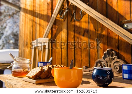 Breakfast on wooden table outside winter snow cottage