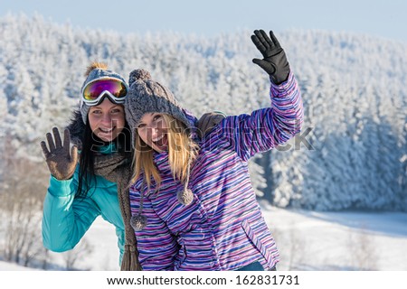 Two female friends enjoy winter snow in mountains holiday break