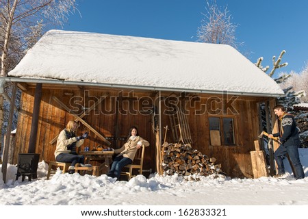 Cozy wooden cottage winter snow three friends sitting outside