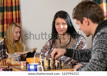 Young couple play chess in winter cottage enjoy holiday