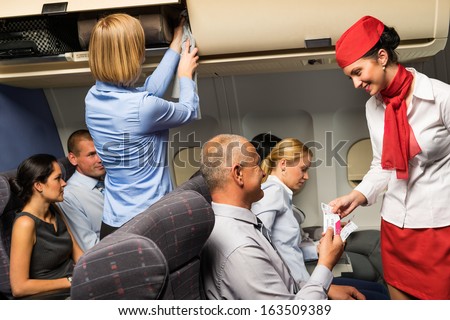 Air Stewardess Check Passenger Ticket In Airplane Cabin Smiling