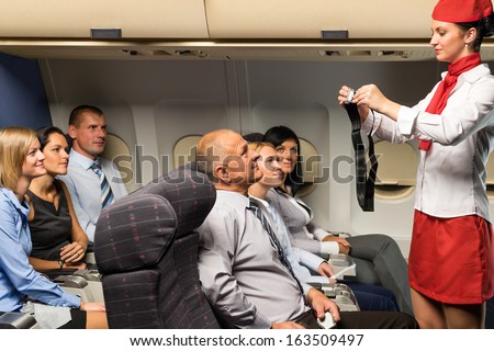 Flight attendant safety demo fastening seat belt passenger airplane cabin