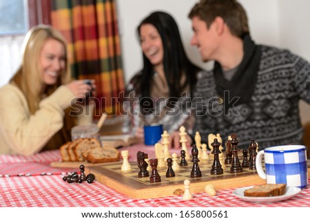 Playing chess cosy winter chalet friends laughing spend holiday
