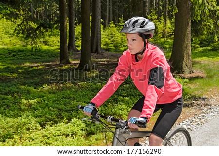 Woman mountain biking in forest on sunny day cycling path