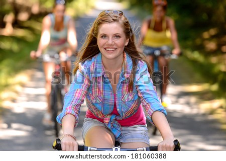 Teenage girl riding bike with friends on countryside road