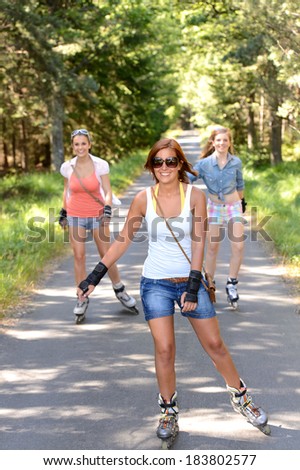 Happy girl friends skating outdoors on countryside road summer sport
